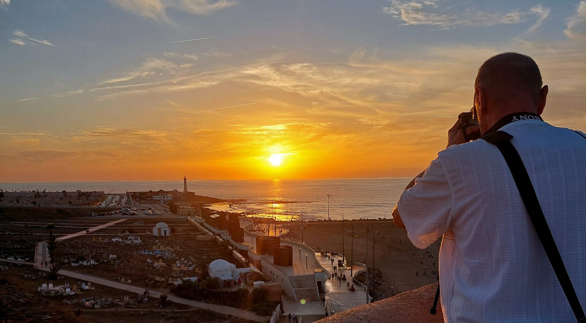 Fotograf robi zdjęcie zachodu słońca nad morzem i latarnią na wybrzeżu – Foto Karol Szczecin