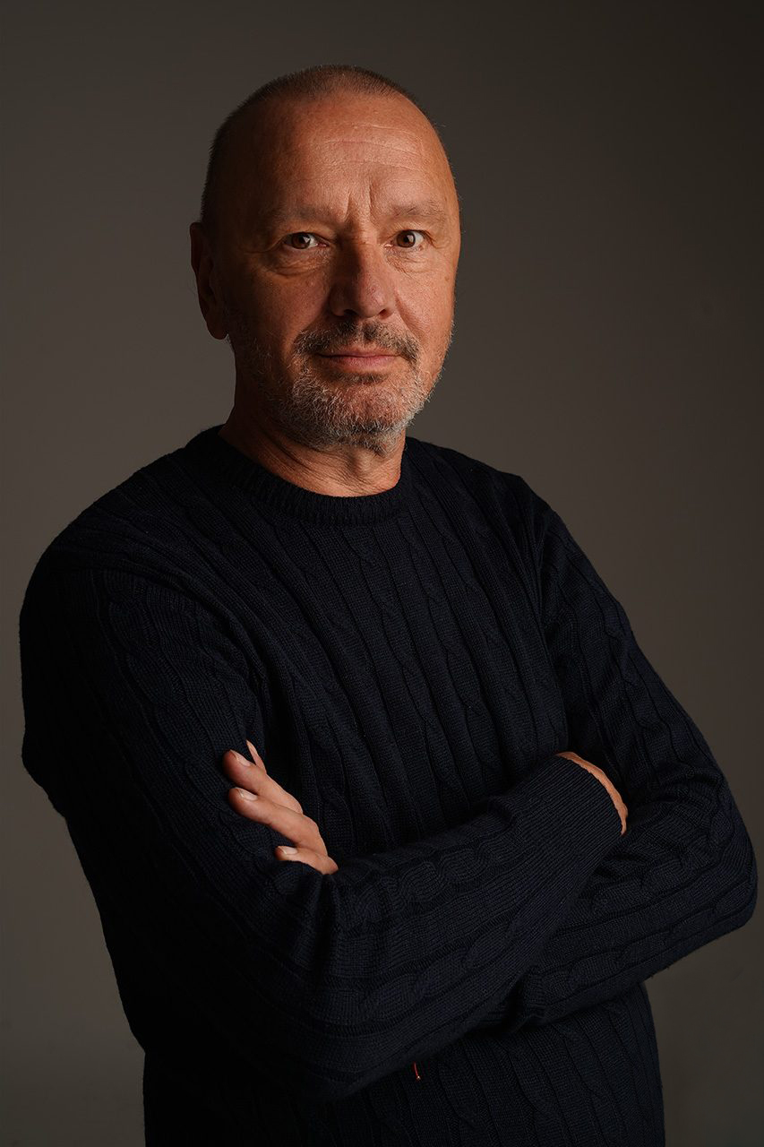Portret fotografa w ciemnym swetrze, ręce skrzyżowane – Foto Karol Szczecin